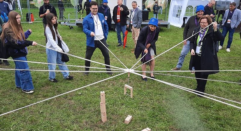 Konfis und Menschen aus der Kirchenleitung beim Spiel Fröbelkran